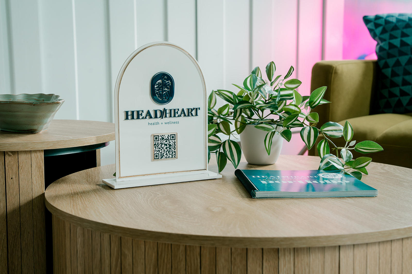 A sign for the business Head and Heart Health and Wellness sits on a table with a plant