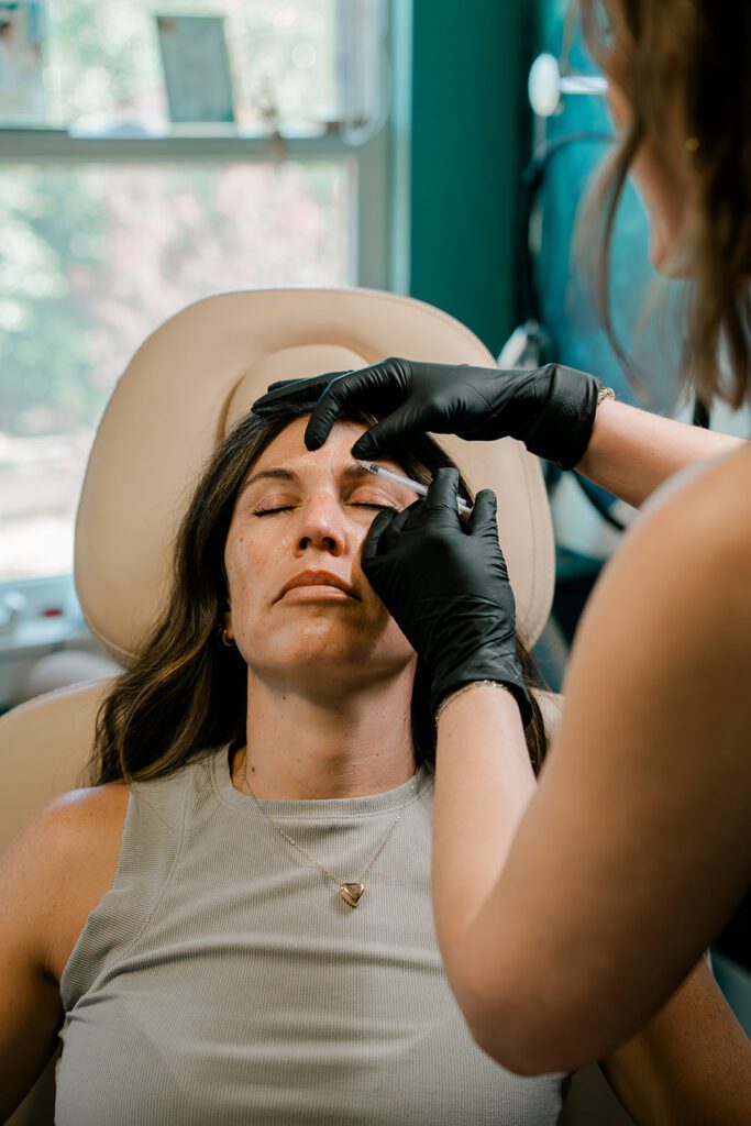 Hands administering botox to a woman in a chair