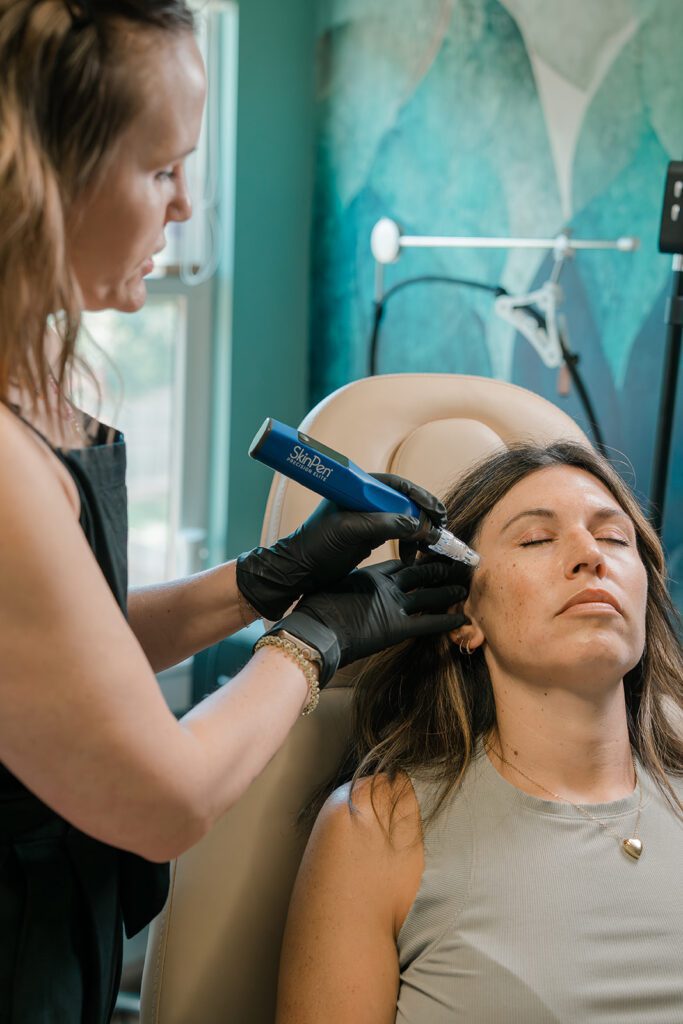 A woman provides a skin pen service to another woman who is sitting in a chair