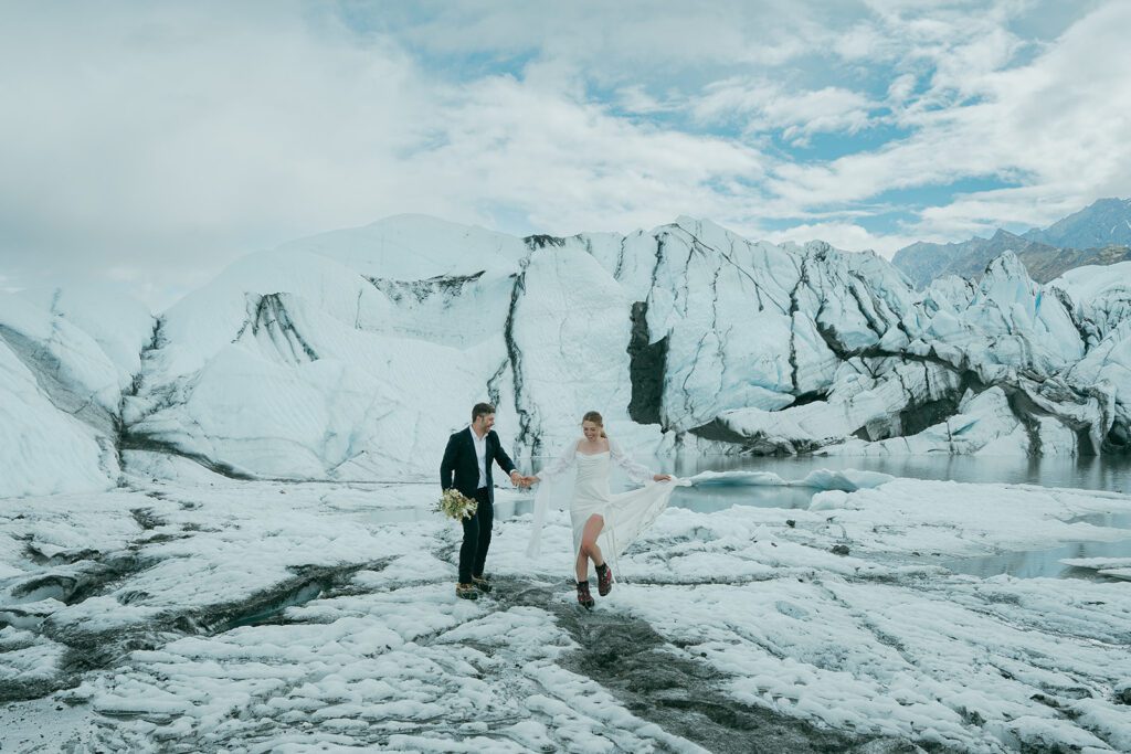 A man and woman in wedding clothing embrace on a glacier in Alaska. 
