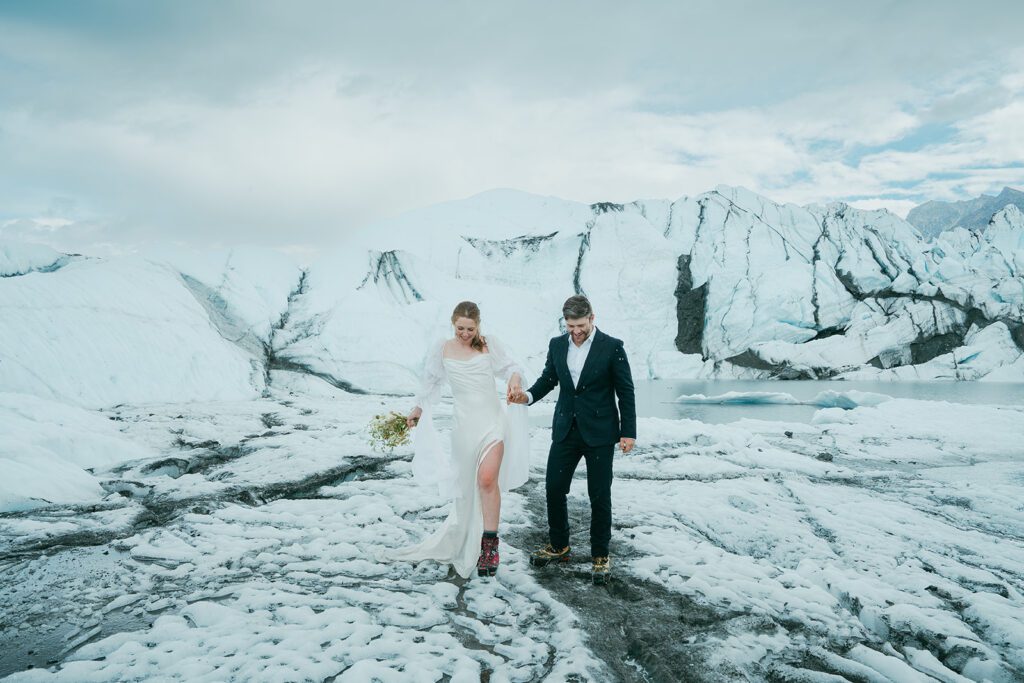 A man and woman in wedding clothing exchange wedding vows on a glacier in Alaska. 