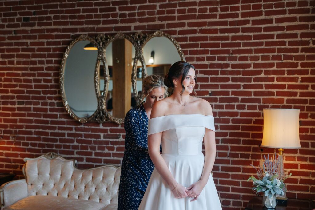 A bride has her gown zipped up in the bridal suite at her kansas city wedding