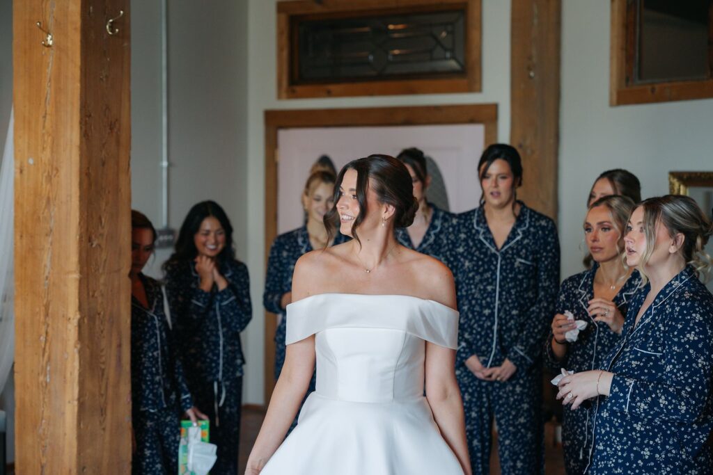 A bride shows off the back of her dress to her bridesmaids at her KC wedding venue