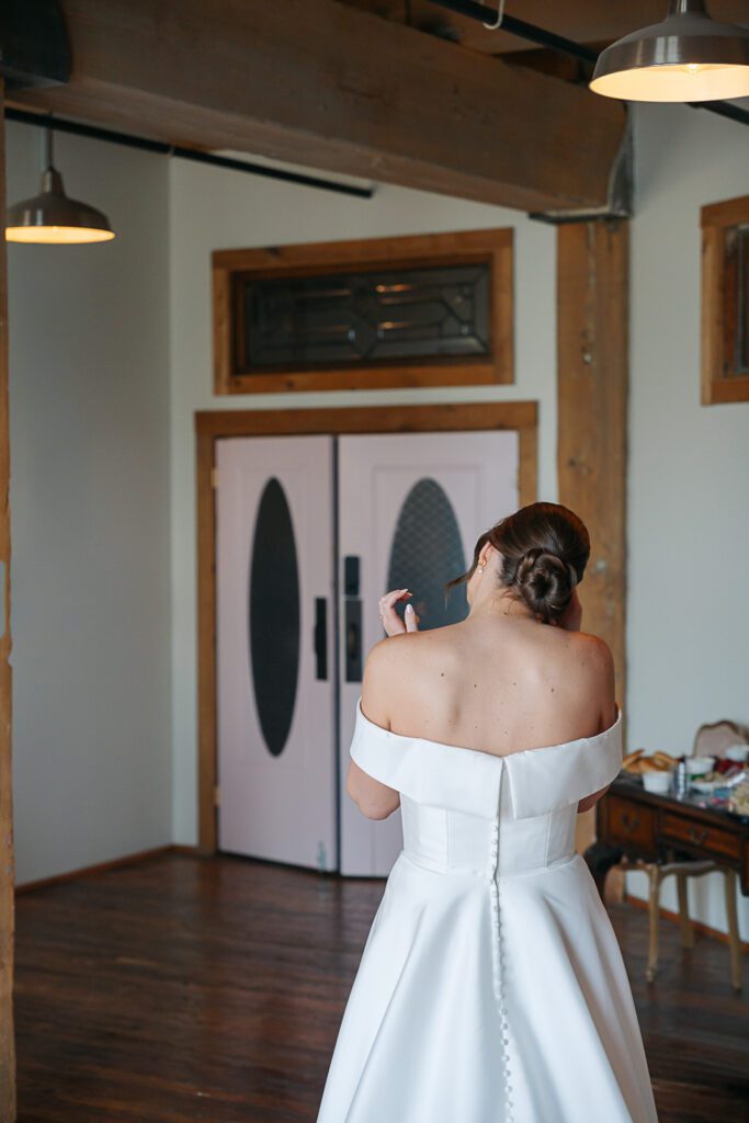 A bride stands in front of pink doors in the bridal suite of her KC wedding venue