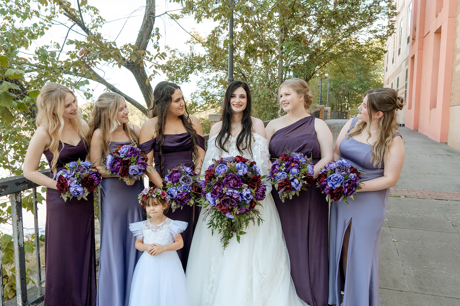 Bridesmaids smile at a bride while standing for a formal portrait