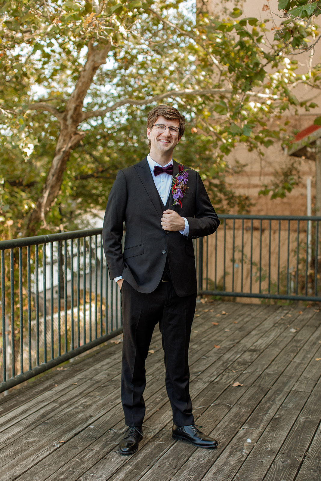 A groom smiles at the camera outside of Lawrence wedding venue, abe and jakes landing 