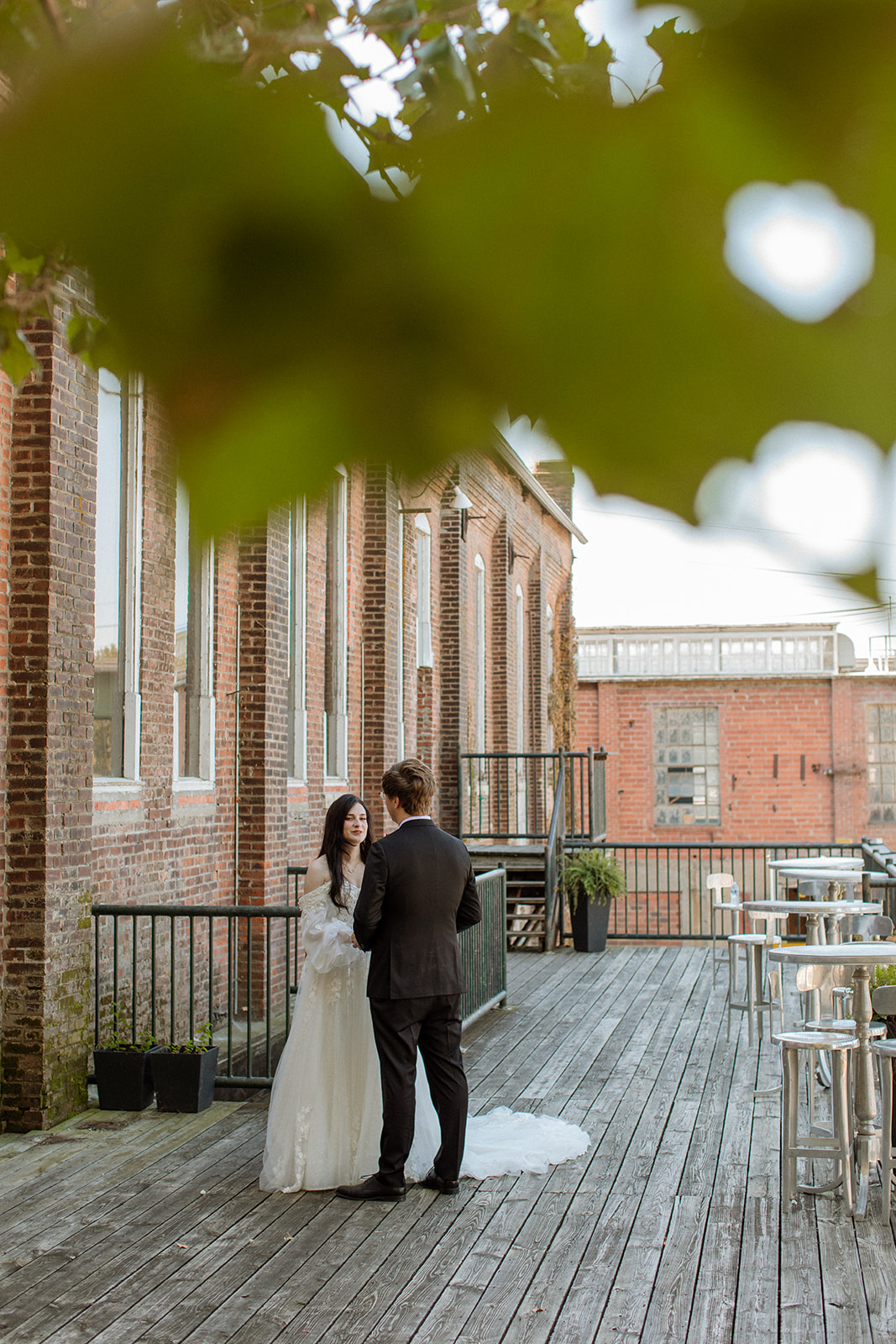 A bride and groom stand on a porch outside of their lawrence wedding venue
