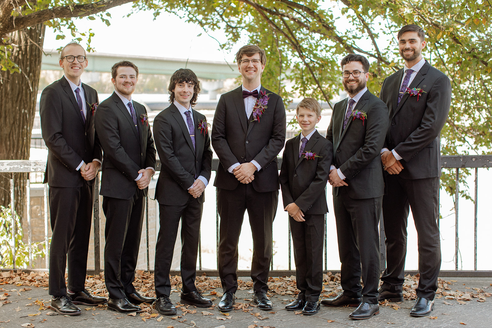 A groom and his groomsmen stand smiling at the camera outside of Lawrence wedding venue