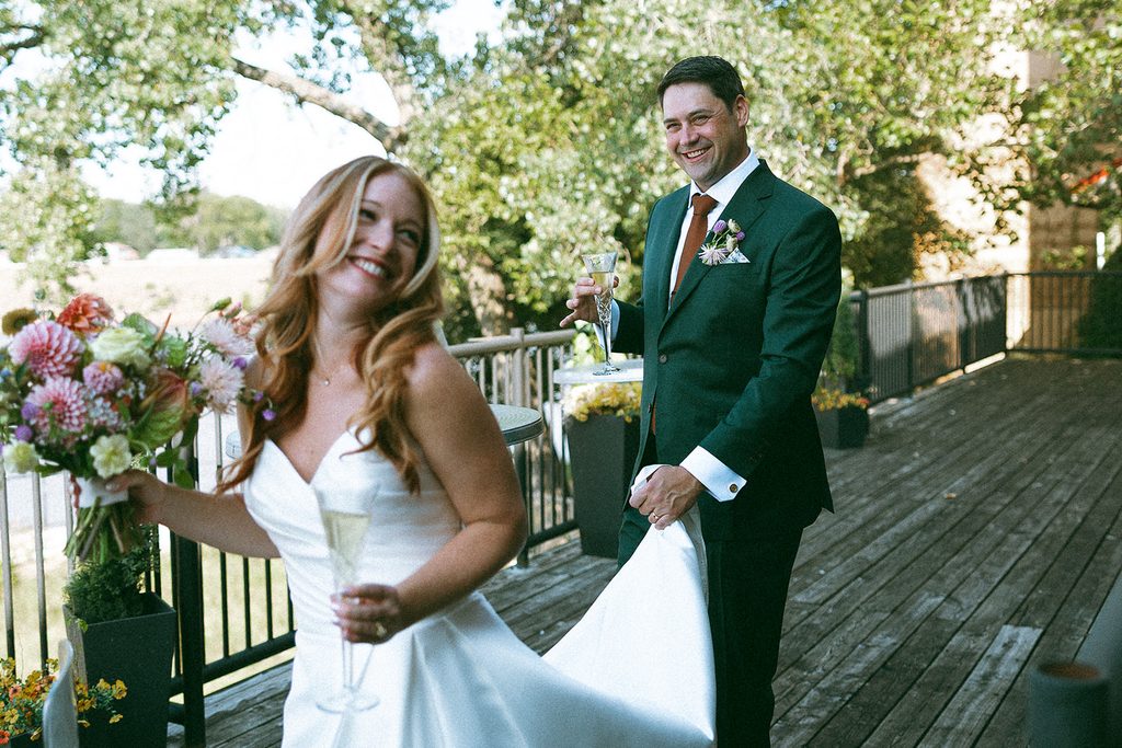 Groom holds back of brides dress while she laughs