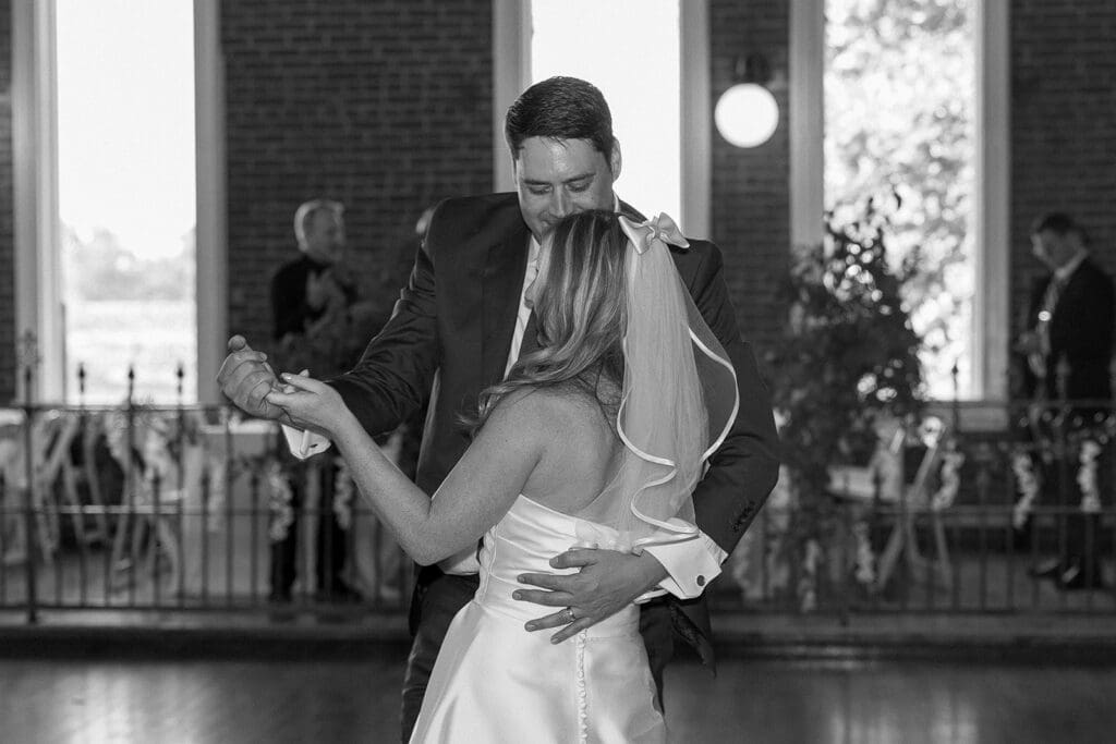 Bride and groom dance while groom looks down at brides face