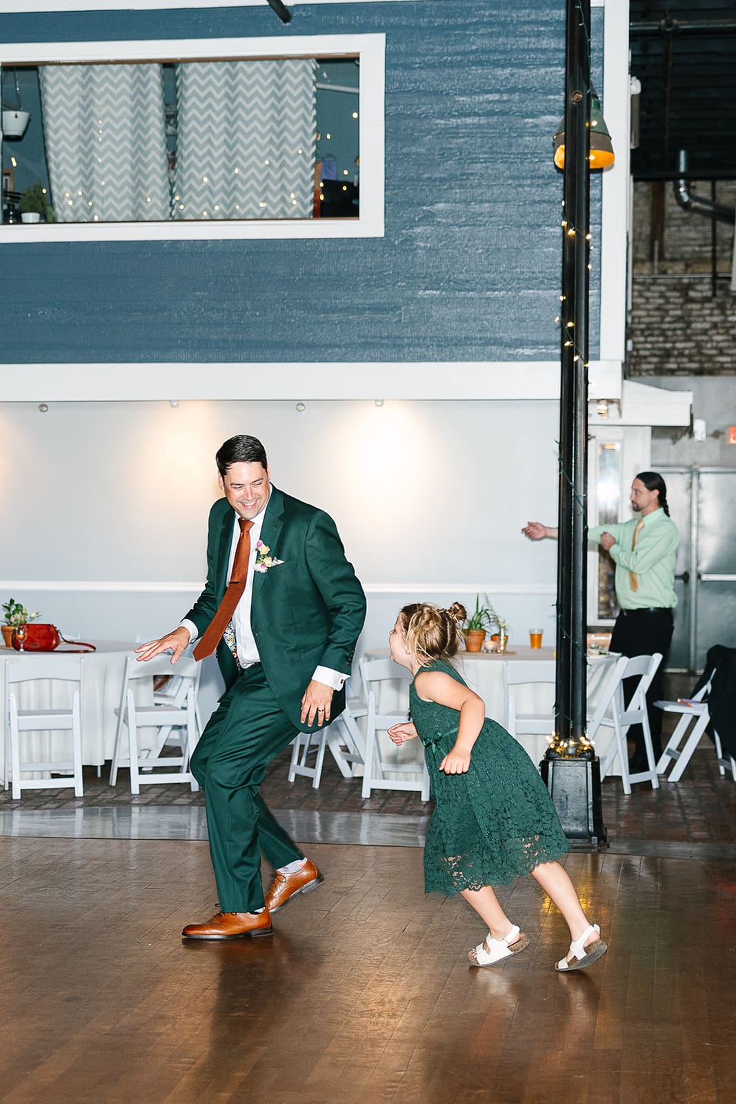 Groom and flower girl play tag on dance floor