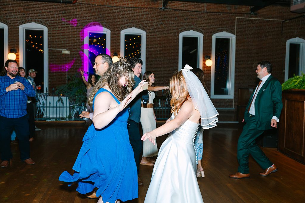 bride and friend dance together