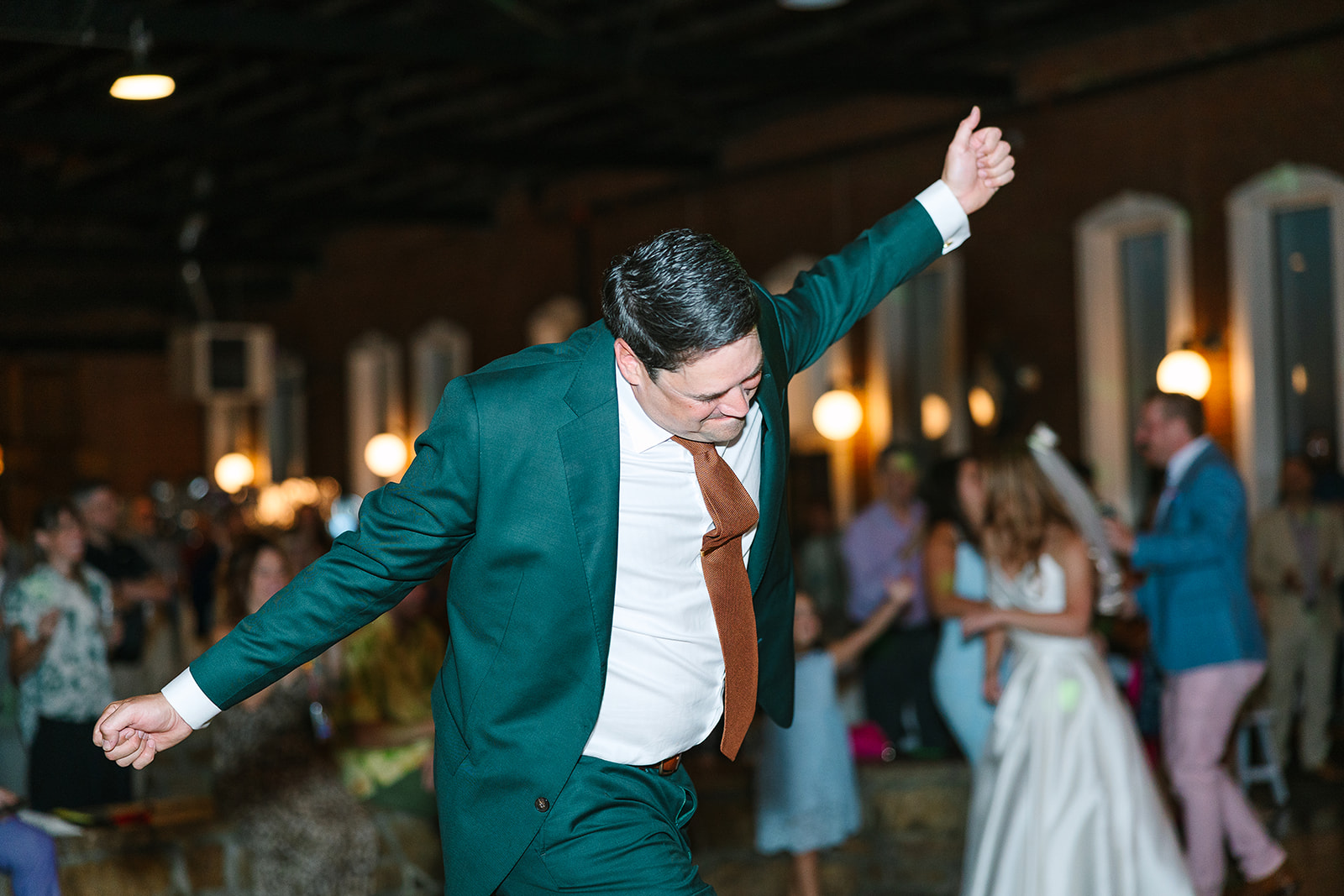 Groom dancing with arms outstretched on the dancefloor