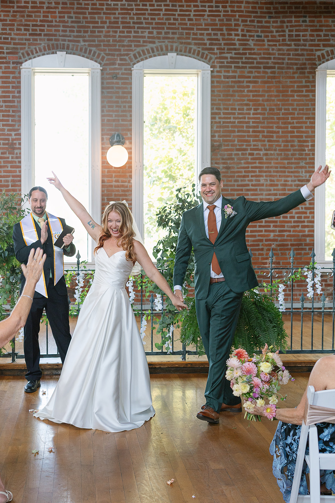 Bride and groom smile and raise arms after getting married