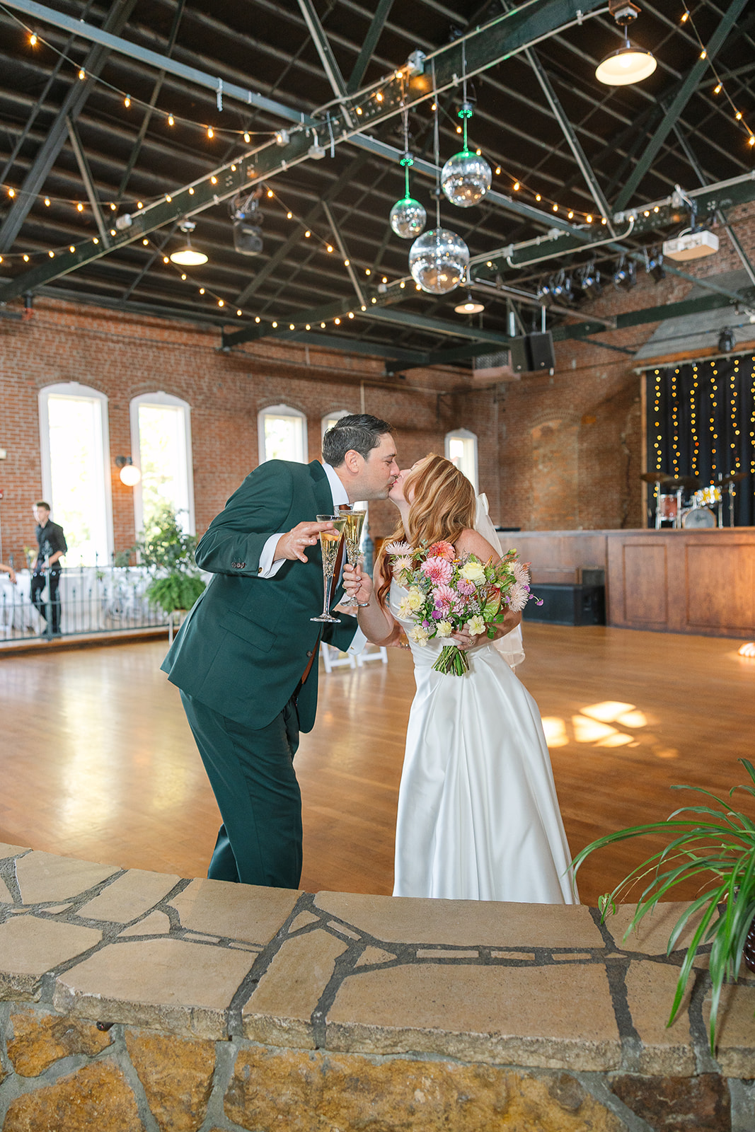 Bride and Groom kiss while holding champagne flutes