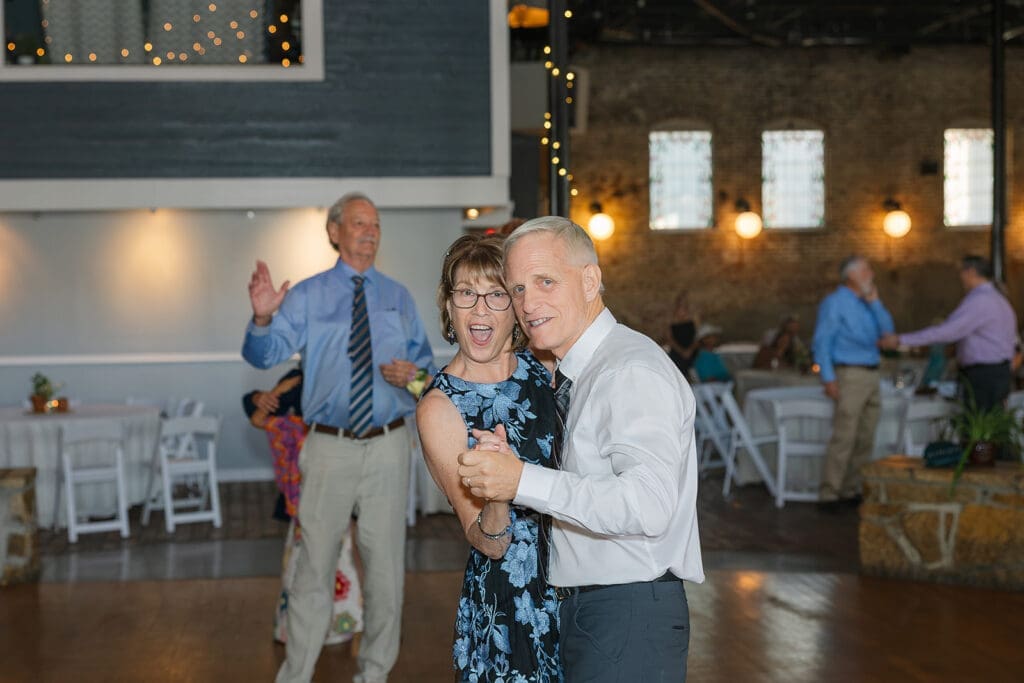 man and woman dance cheek to cheek and smile at camera