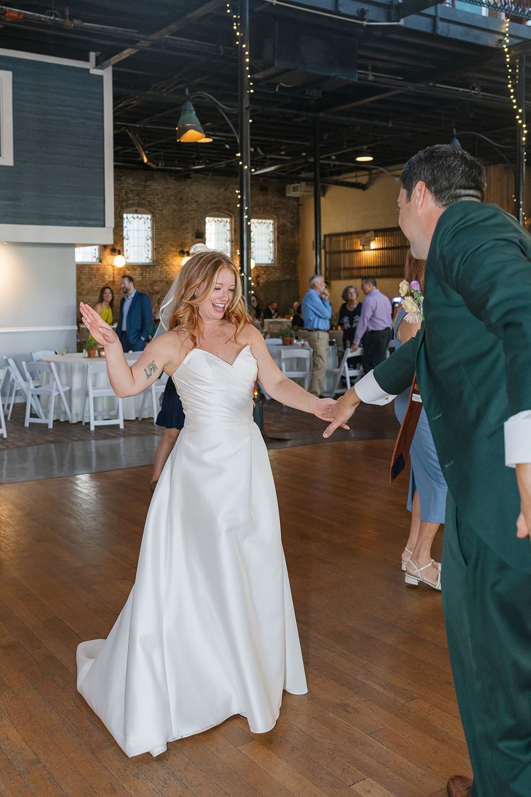 Bride smiles while dancing with groom
